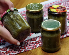 Ароматні брусочки маринованих огірків із кунжутом та часником у скляній банці на дерев'яному столі.
