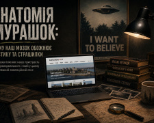 Атмосферний стіл журналіста в темній кімнаті під лампою, на якому лежить ноутбук із сайтом Kamianske-City та стос книг про міські легенди, фольклор і психологію страху, на стіні постер «I want to believe».