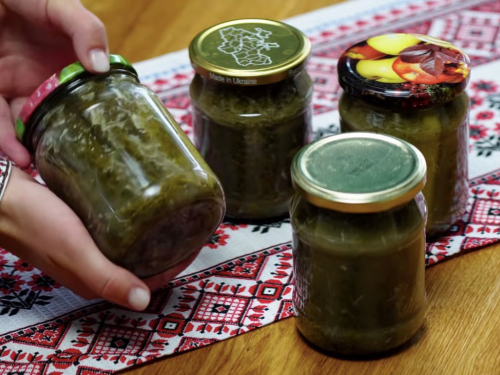Ароматні брусочки маринованих огірків із кунжутом та часником у скляній банці на дерев'яному столі.