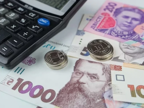 Гривневі банкноти та розрахунковий листок із зарплатою