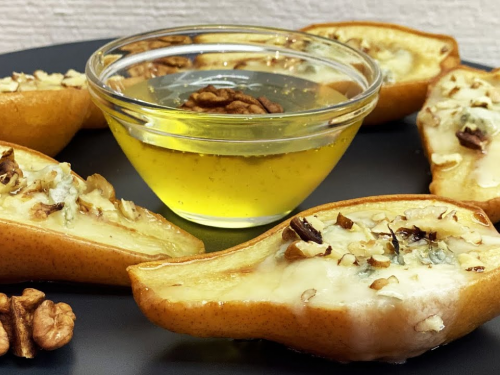 Запечені груші з медом, волоськими горіхами і корицею на тарілці