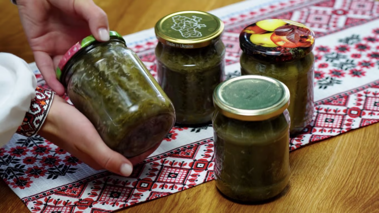 Ароматні брусочки маринованих огірків із кунжутом та часником у скляній банці на дерев'яному столі.
