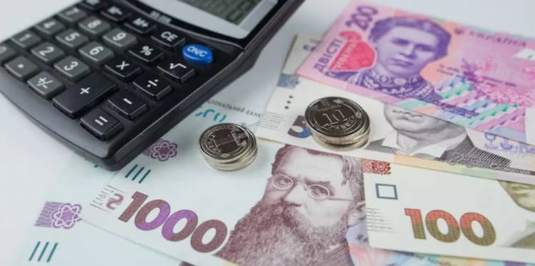 Гривневі банкноти та розрахунковий листок із зарплатою